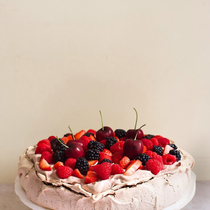 Chocolate pavlova topped with blackberry, cherry, raspberry, and strawberry.