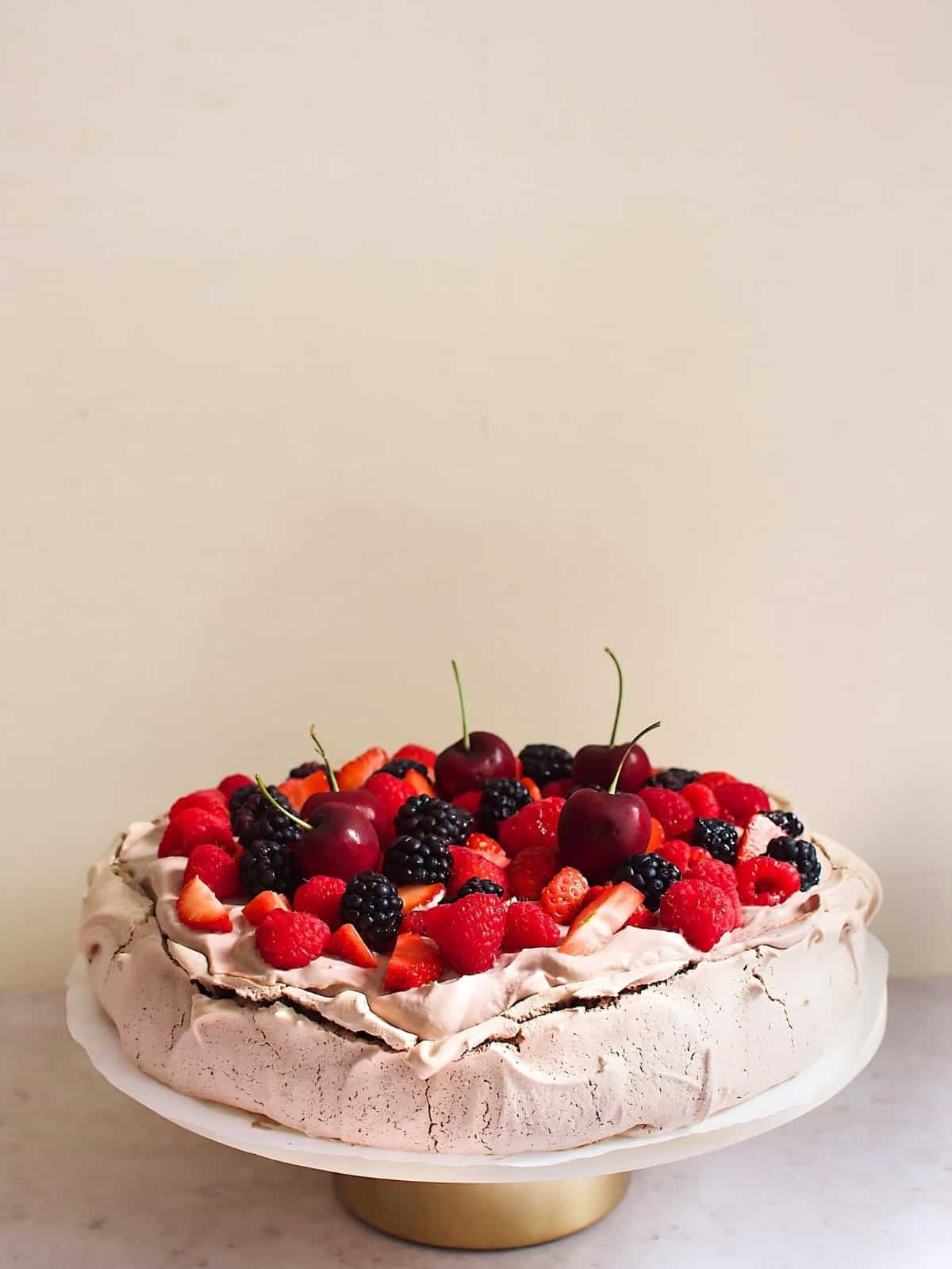 Chocolate pavlova topped with blackberry, cherry, raspberry, and strawberry.