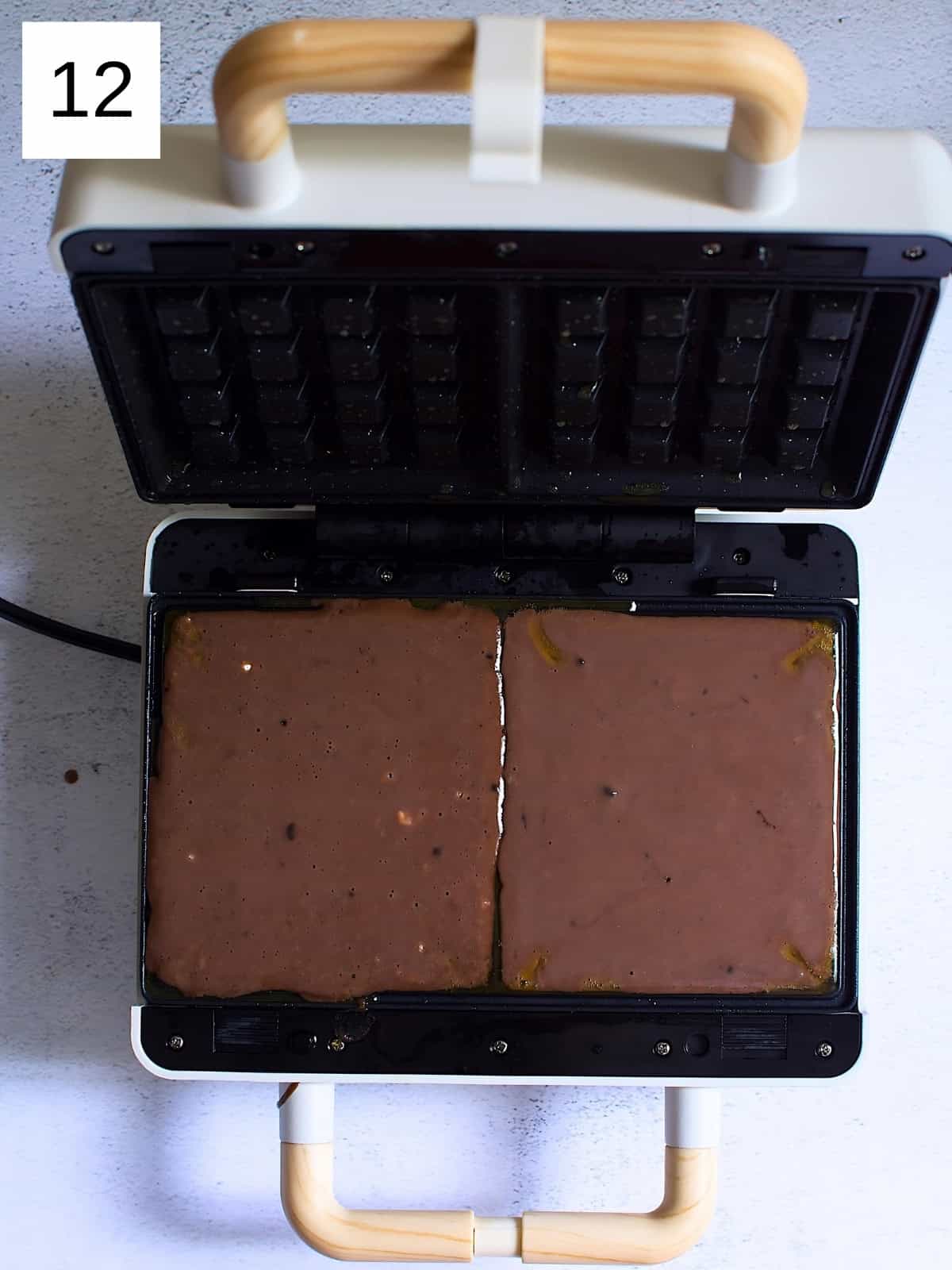 Chocolate waffle batter in a waffle maker.