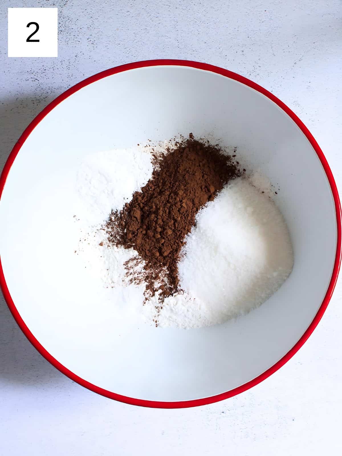 A bowl of white sugar, cocoa powder, all purpose flour, and salt.