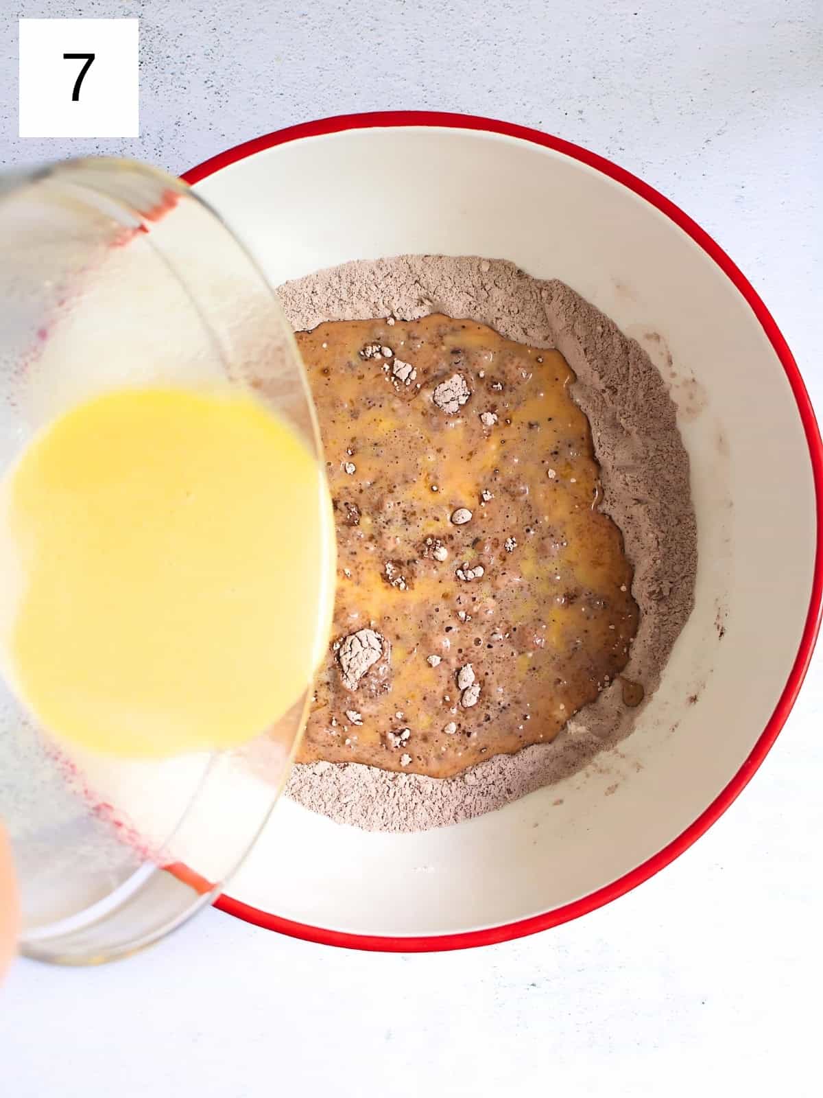 Waffle batter being poured in a bowl of cocoa mixture.