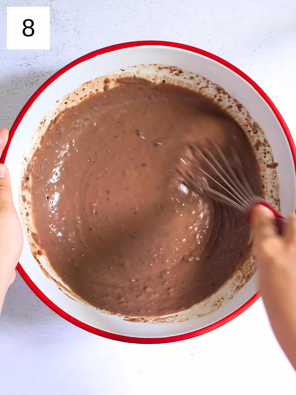 Cocoa mixture and waffle batter being whisked in a bowl.