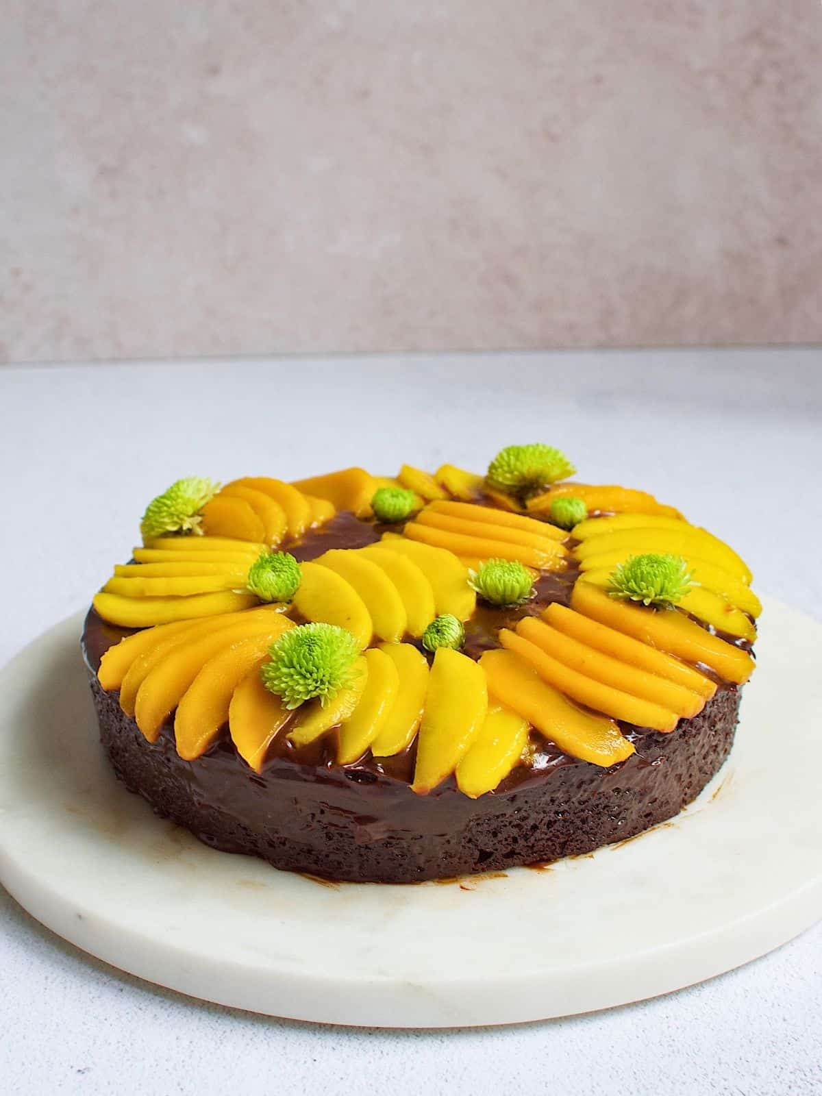 Chocolate mango cake toped with mangoes on a plate.