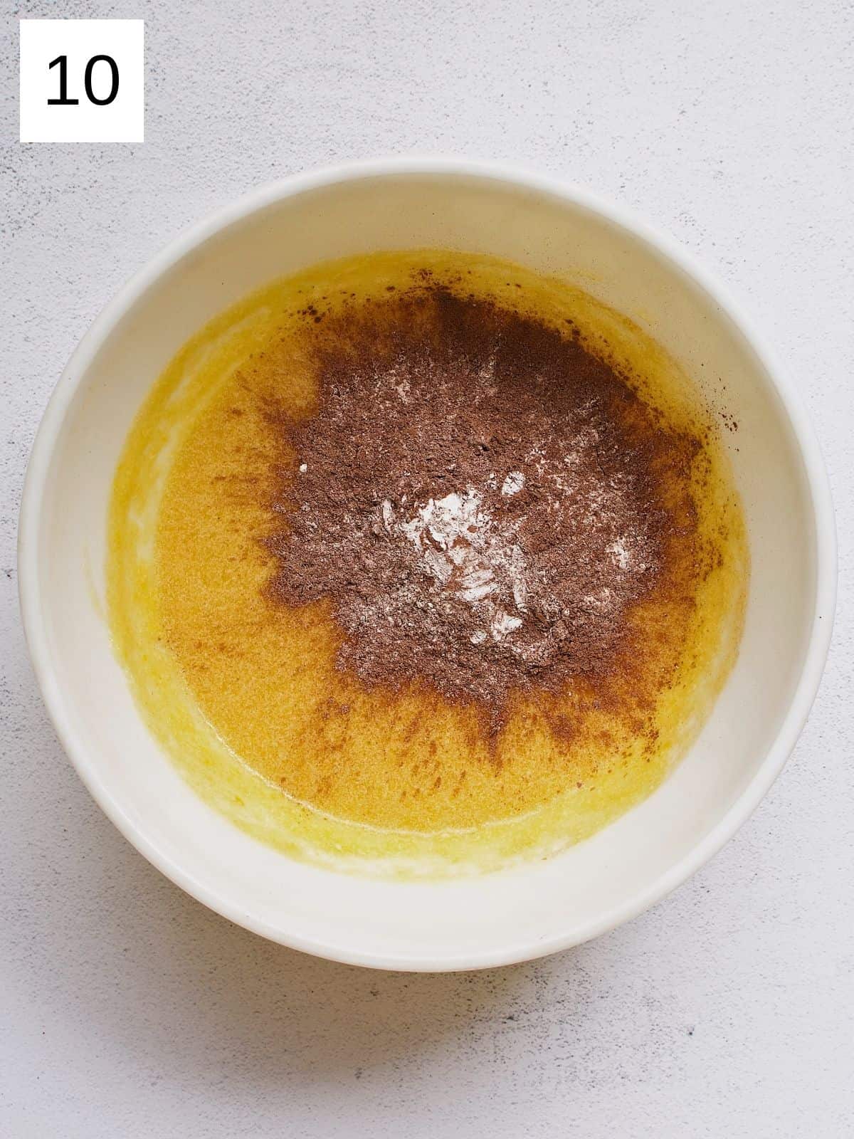 Dry and wet ingredients for chocolate mango cake combined in a bowl.