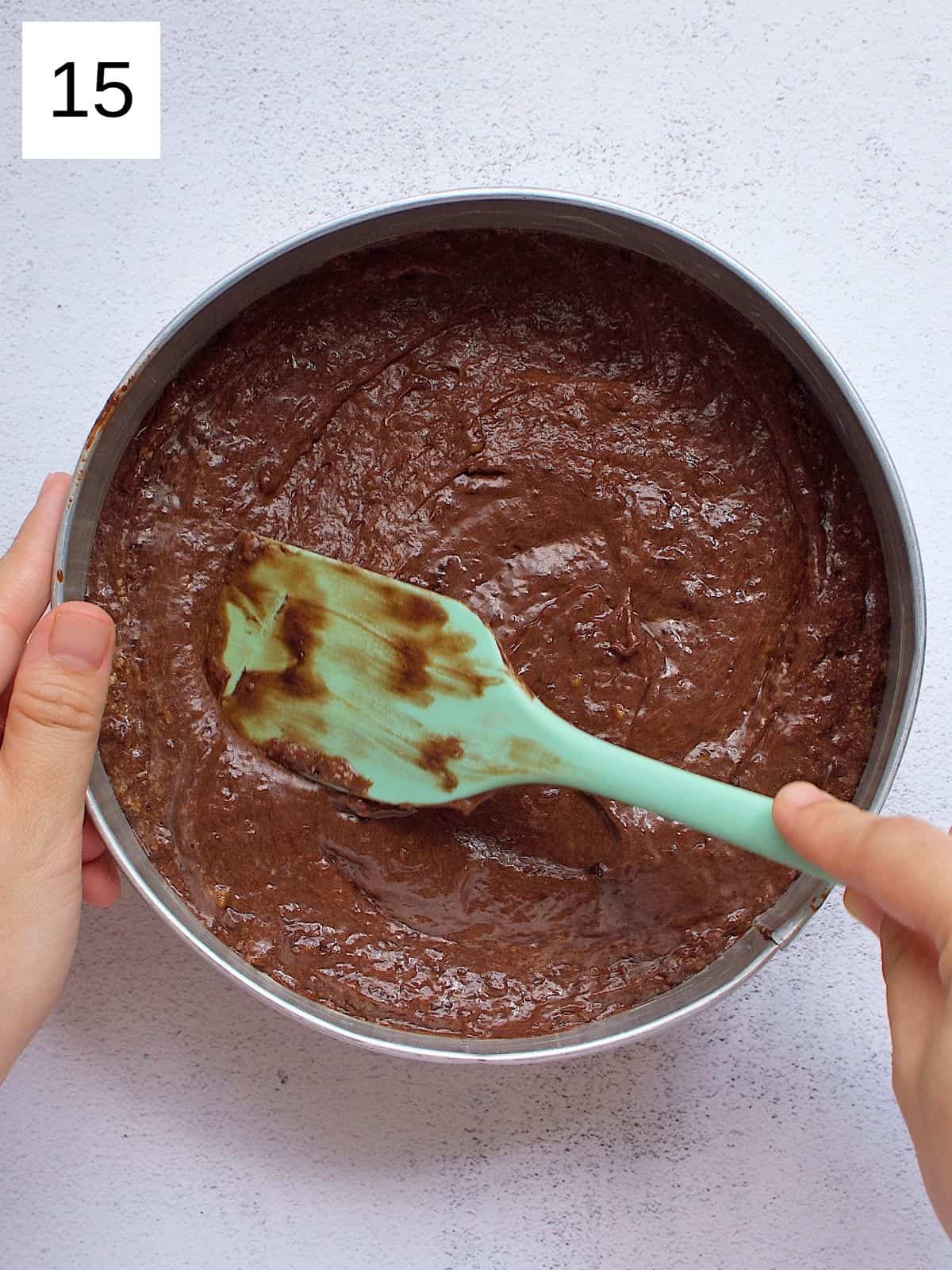 Chocolate mango cake batter spreading evenly in a cake pan.