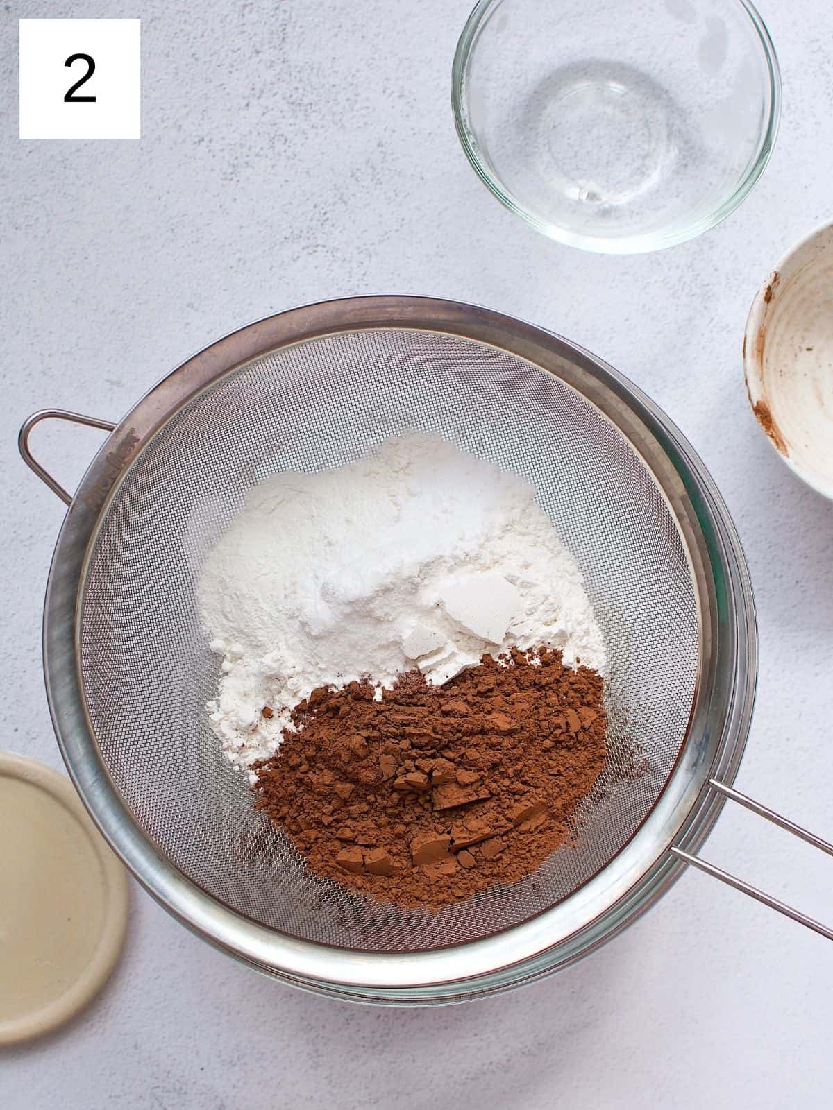 Flour, cocoa powder, baking powder, baking soda, and salt in a sift.