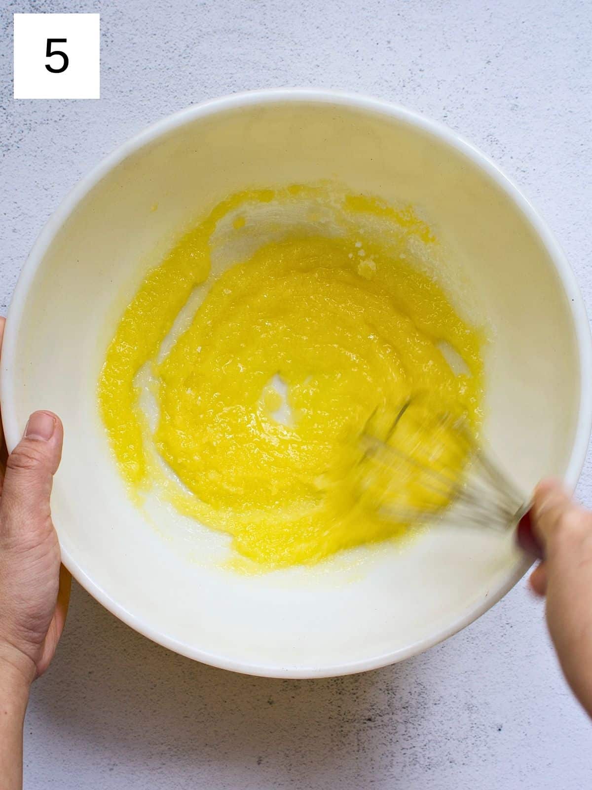 A person whisking melted butter and sugar.