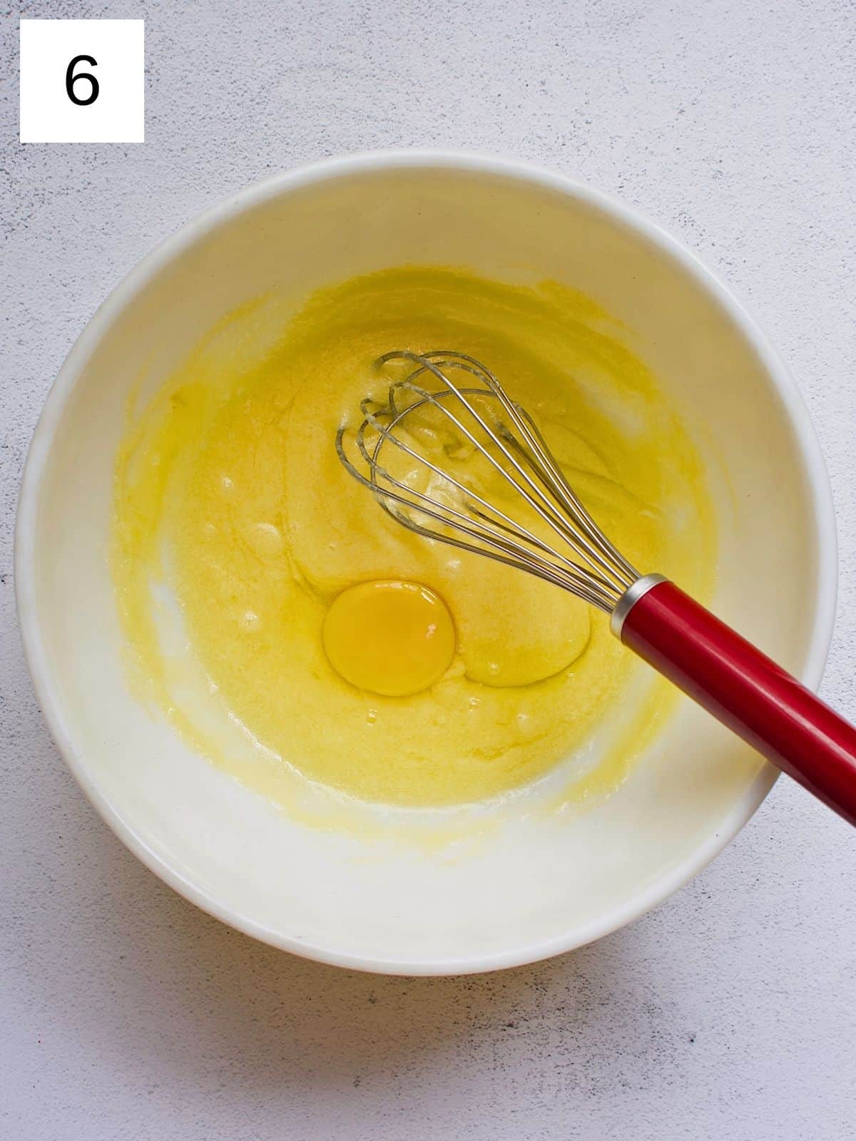 A person about to whisk melted butter, sugar, and egg.