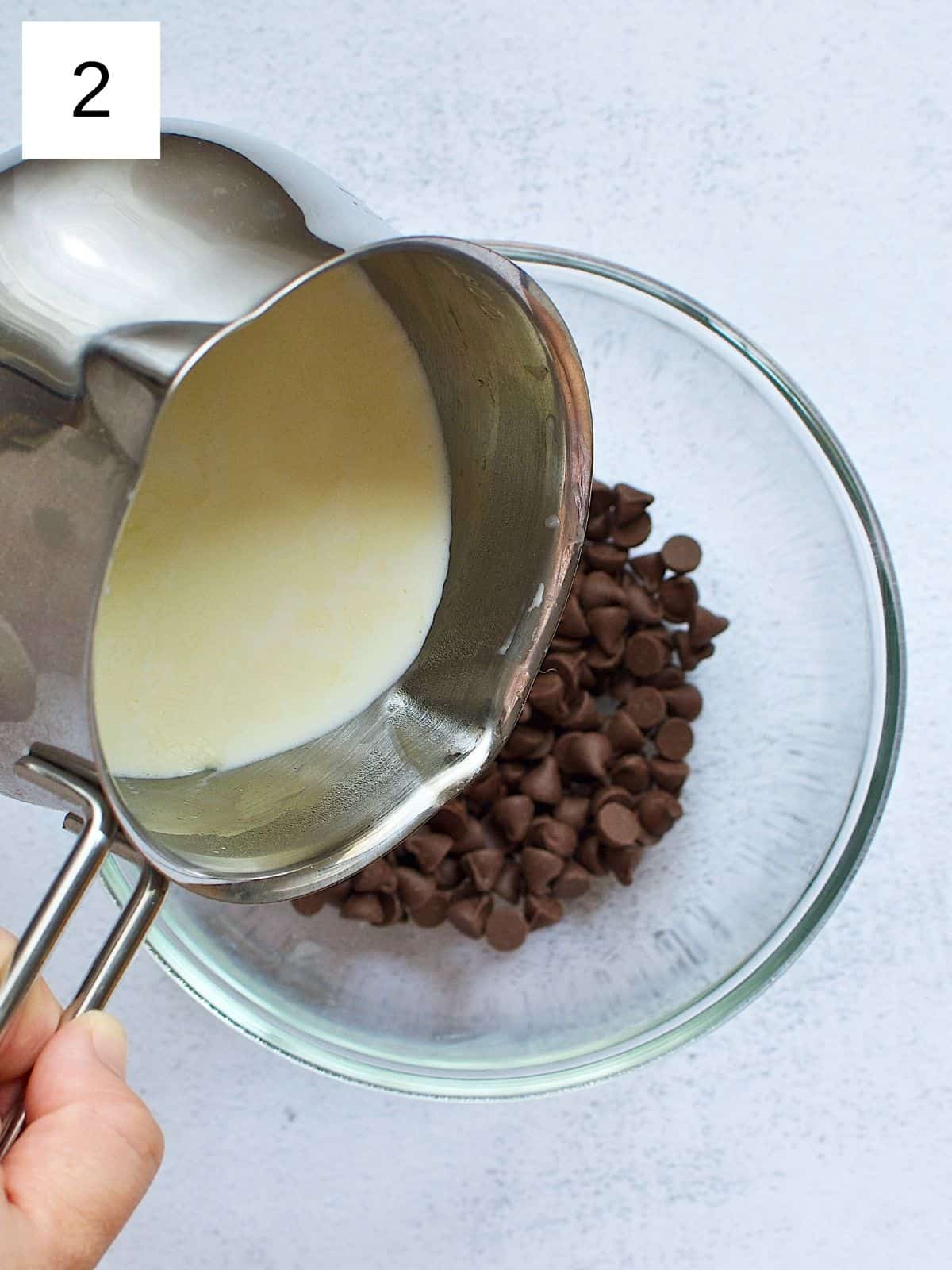 Heated heavy cream pouring on top of a bowl of chocolate chips.