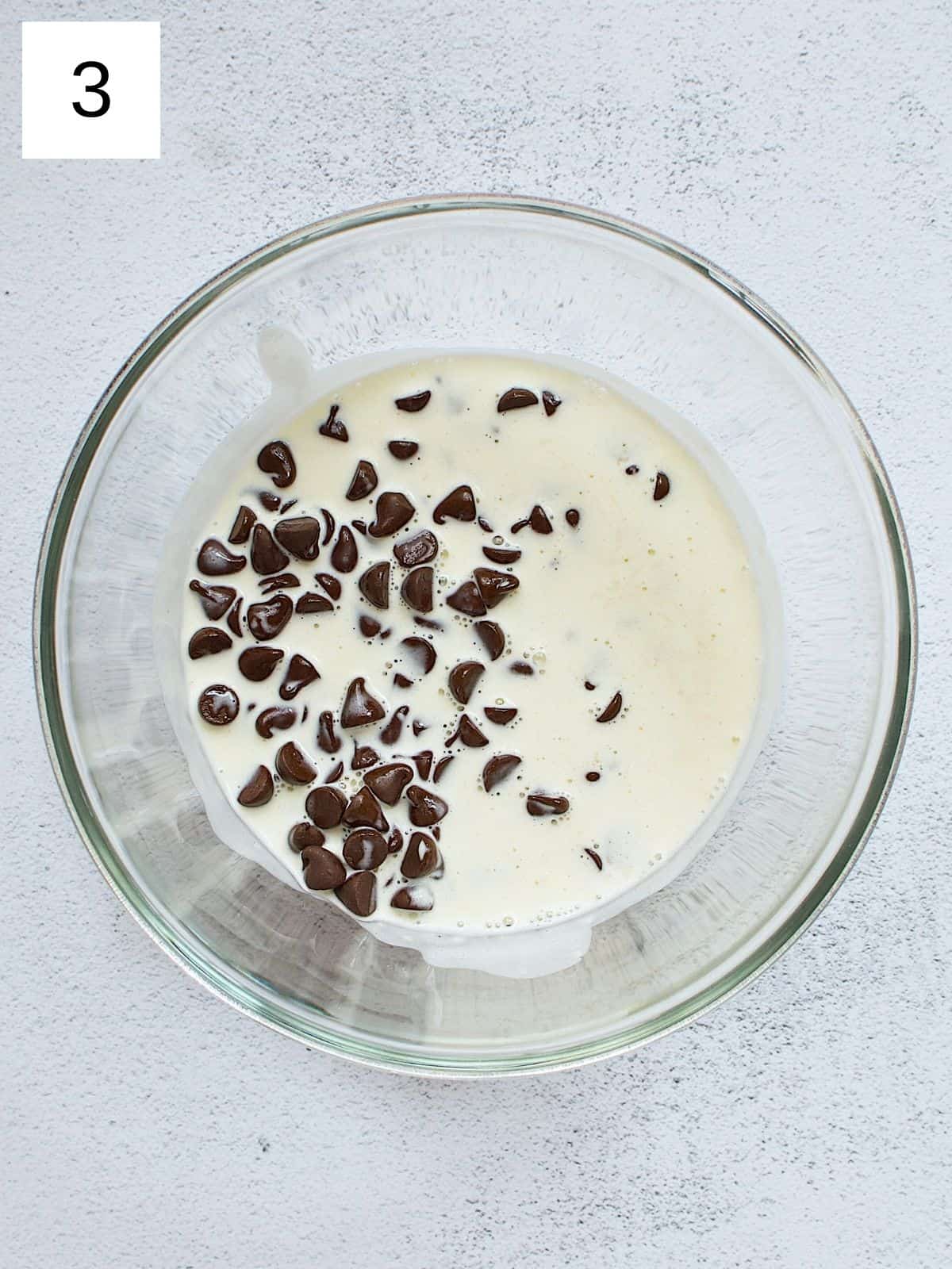 A bowl of chocolate chips submerged in heated heavy cream.