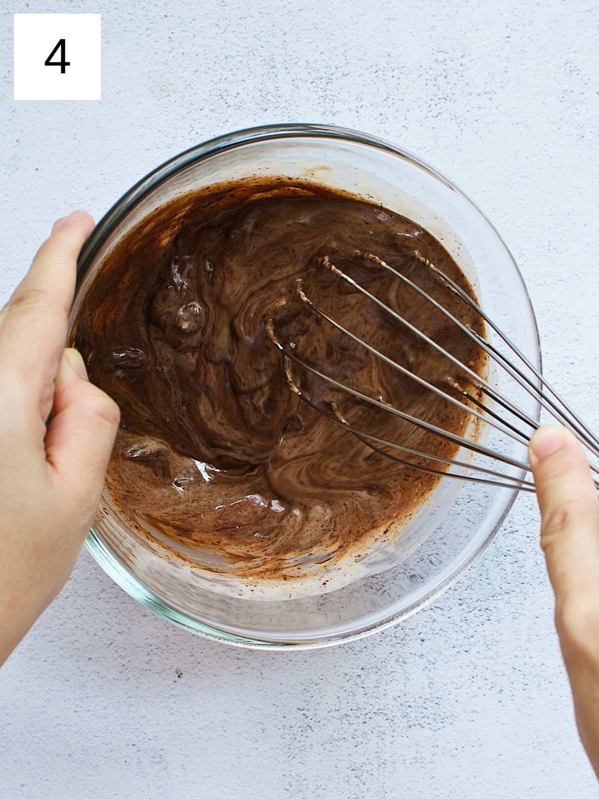 A person whisking melted chocolate chips and heavy cream.