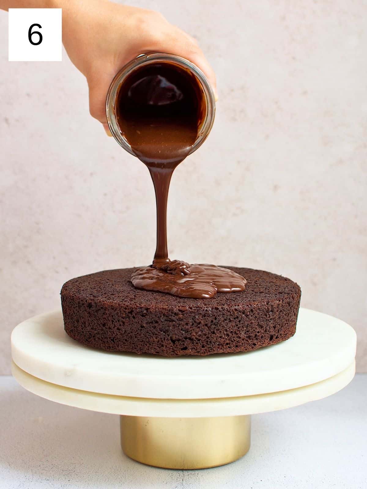 Chocolate ganache being poured on a chocolate cake.