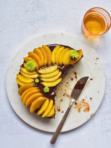 Chocolate mango cake on a plate topped with sliced mangoes.