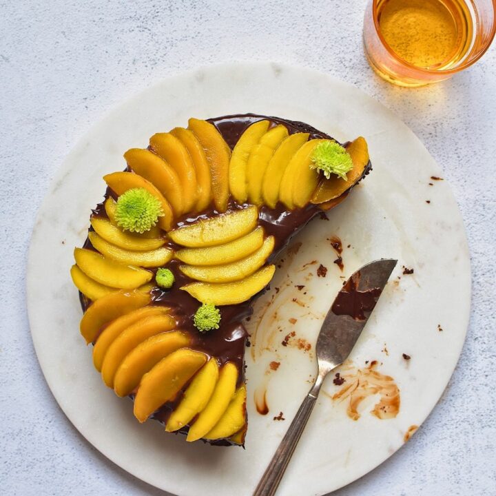 Chocolate mango cake on a plate topped with sliced mangoes.