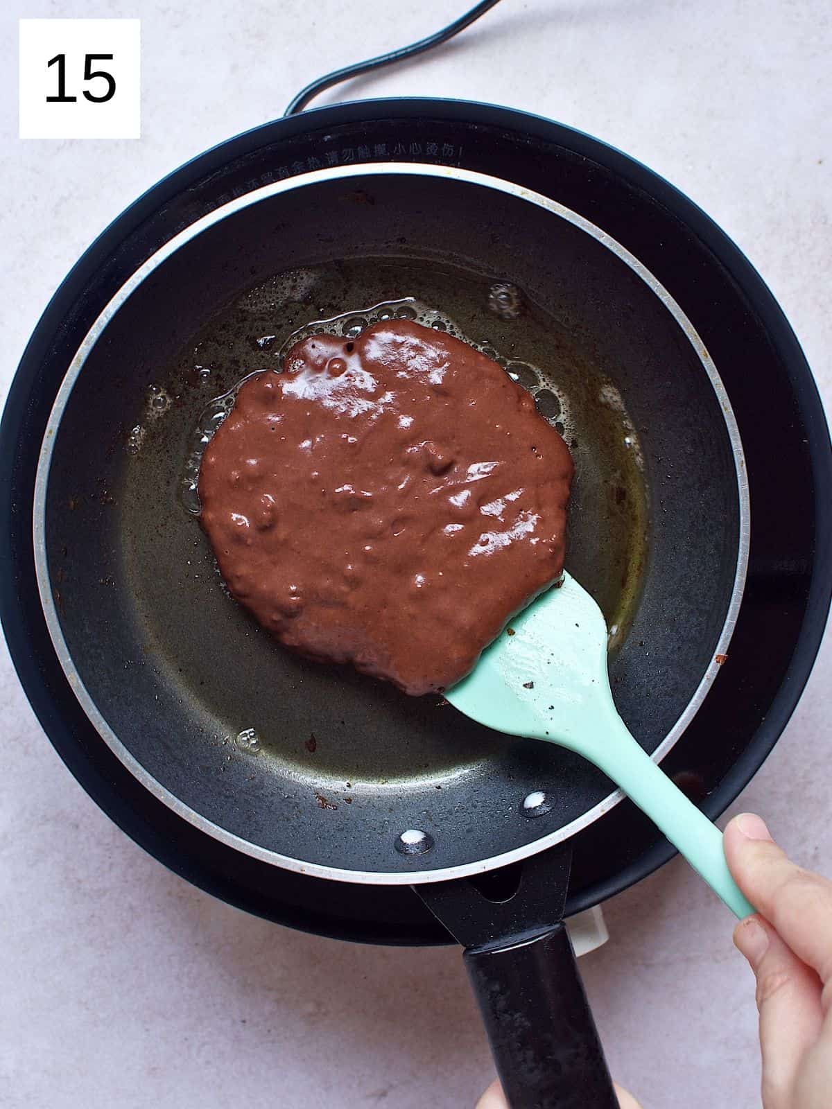 A person flipping chocolate pancakes.