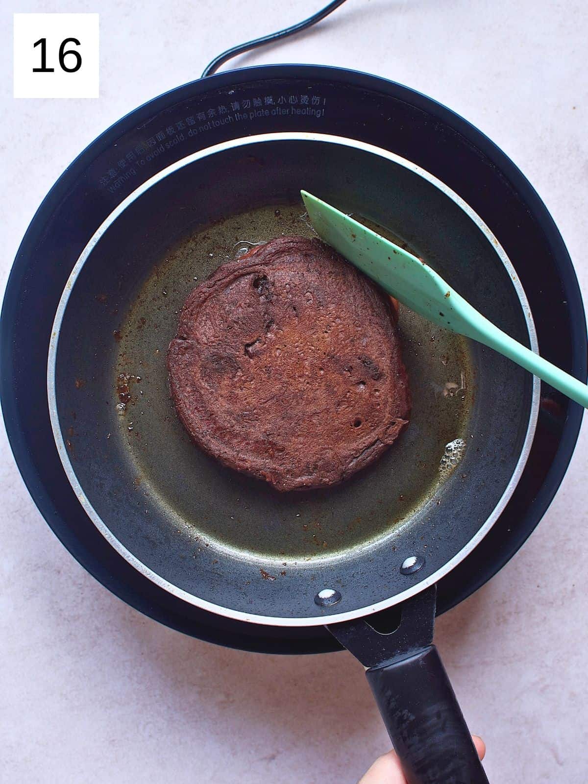 Flipped chocolate pancakes on a skillet.