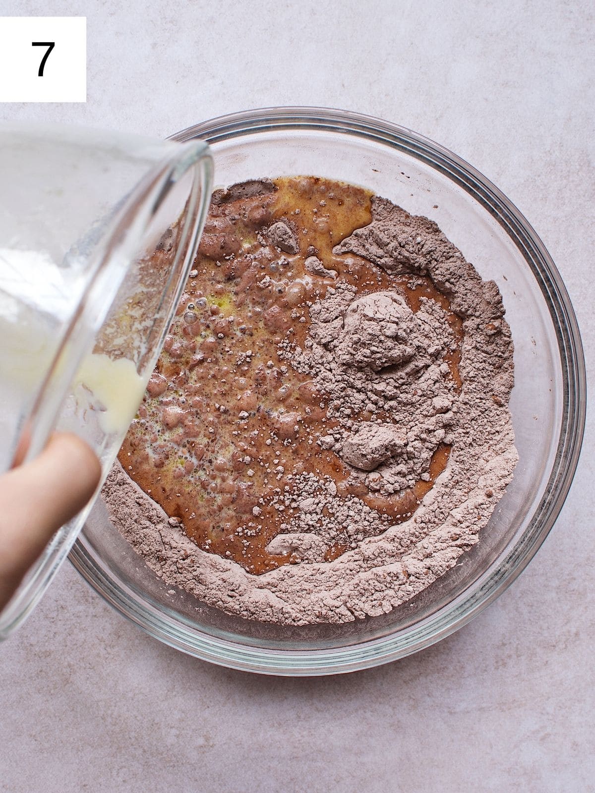 A person pouring the wet ingredients into the dry ingredients.