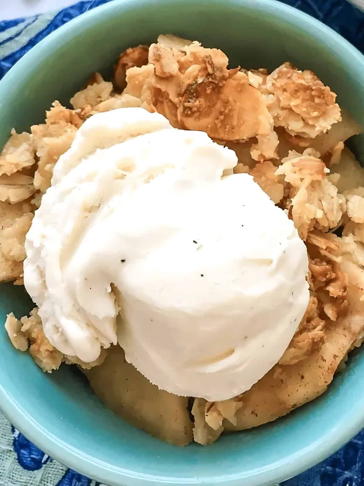 A bowl of apple crisps topped with a scoop of ice cream.