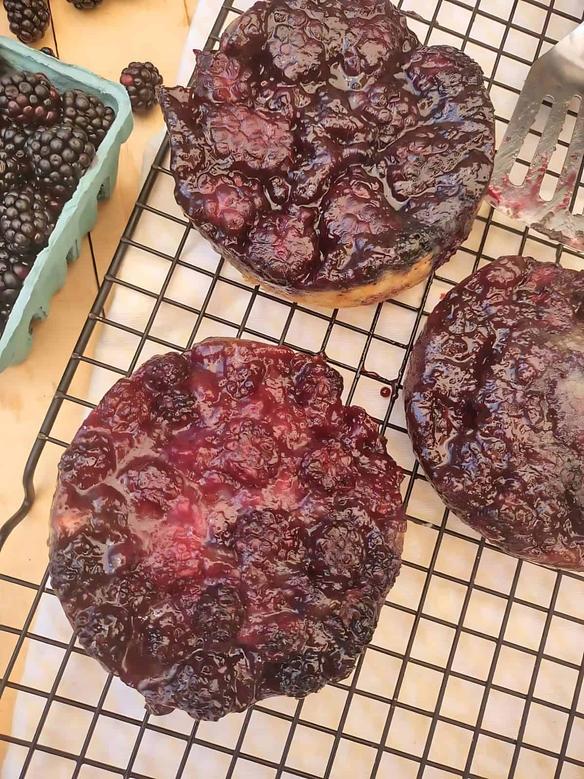 Blackberry upside down cakes on a tray next to blackberries.