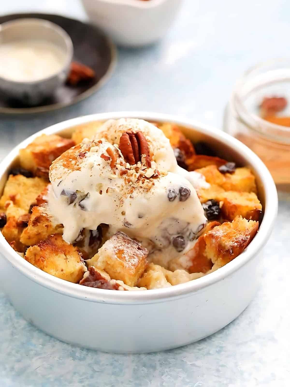 A bowl of bread pudding topped with cream and nuts.