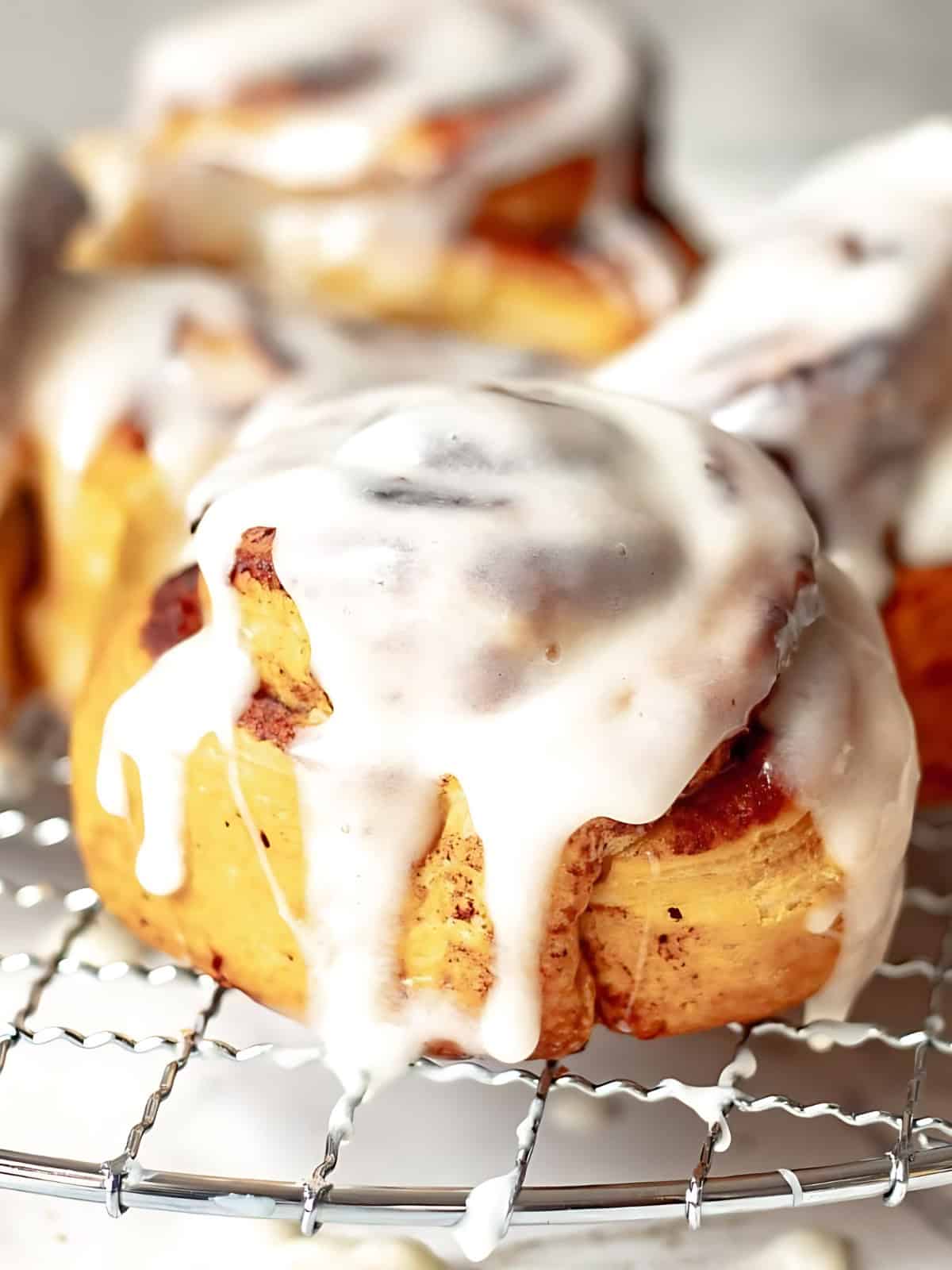 Cinammon rolls on a try drizzled with white icing.