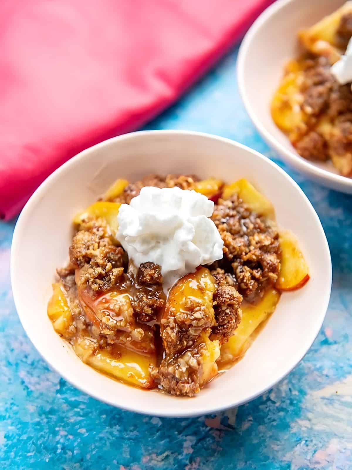 A bowl of peach cobbler topped with frosting.