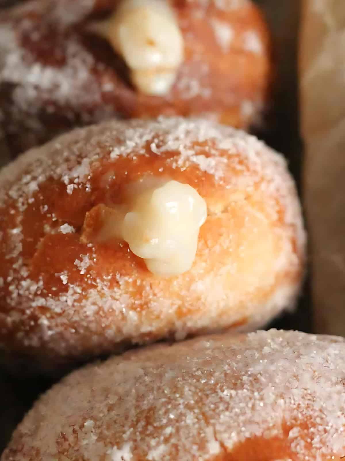 Vegan donuts with custard filling covered with powdered sugar.