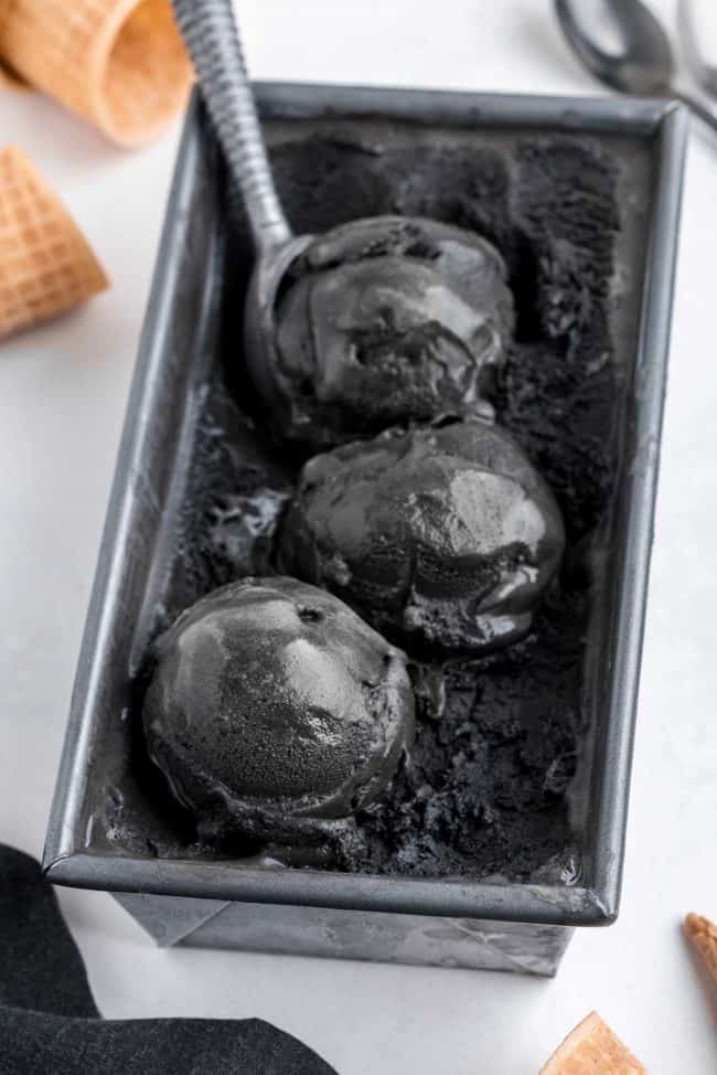 Scoops of black ice cream in a tray.