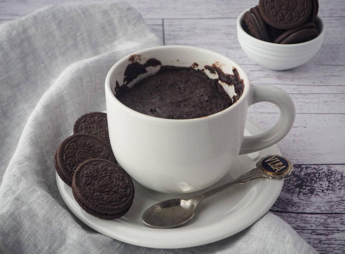 Oreo mug cake in a mug next to oreos.