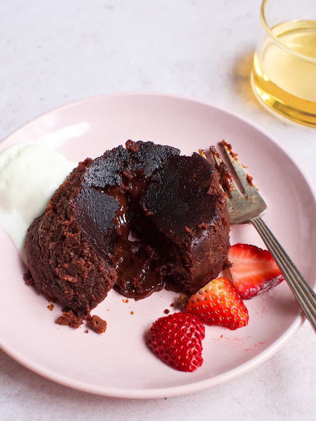 A delicious chocolate lava cake on a plate, served with fresh strawberries for a delightful dessert presentation.