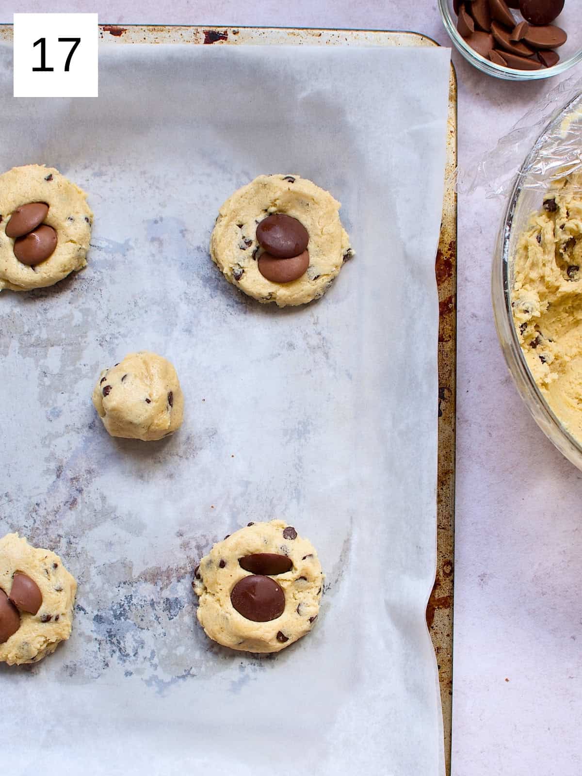 Perfectly scooped cookie batter on a baking tray, topped with chocolate pieces, ready to be baked into delicious, golden cookies.