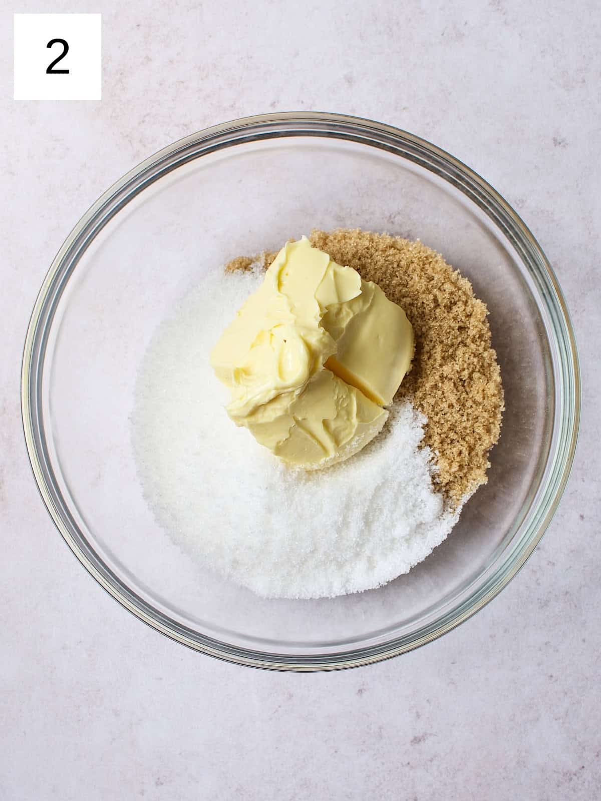 A bowl filled with softened butter, granulated sugar, and brown sugar.