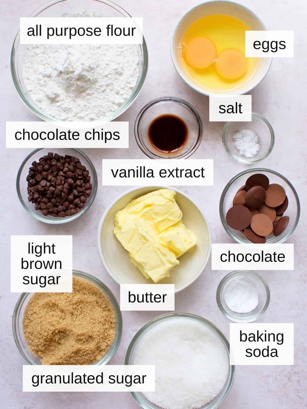 Ingredients for chocolate-filled cookies, including all purpose flour, eggs, salt, chocolate chips, vanilla extract, chocolates, light brown sugar, butter, baking soda, and granulated sugar.