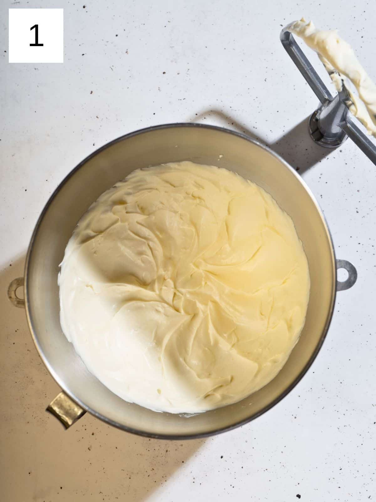 A large mixing bowl filled with whipped cream cheese and butter, ready to be used in a delicious frosting or dip.