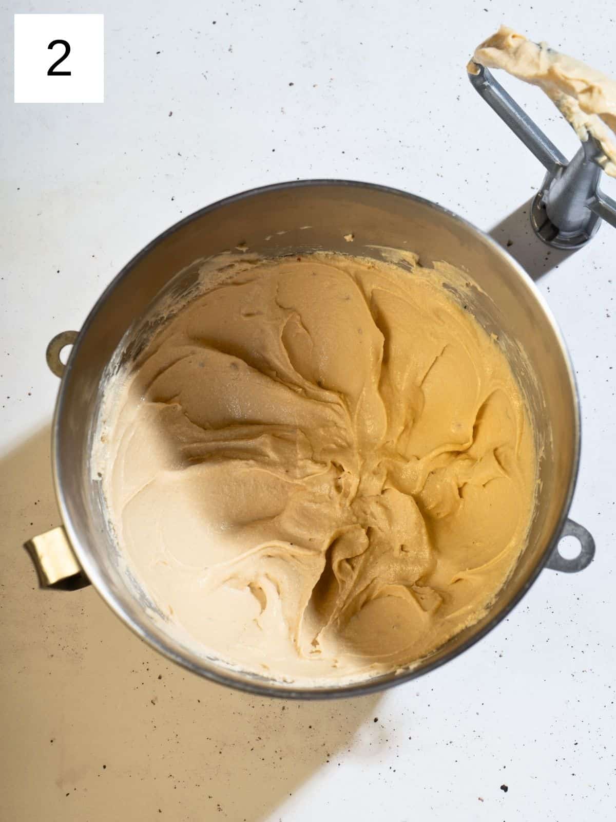 A large mixing bowl filled with whipped cream cheese ,butter, powdered sugar and brown sugar, ready to be used in a delicious frosting or dip.