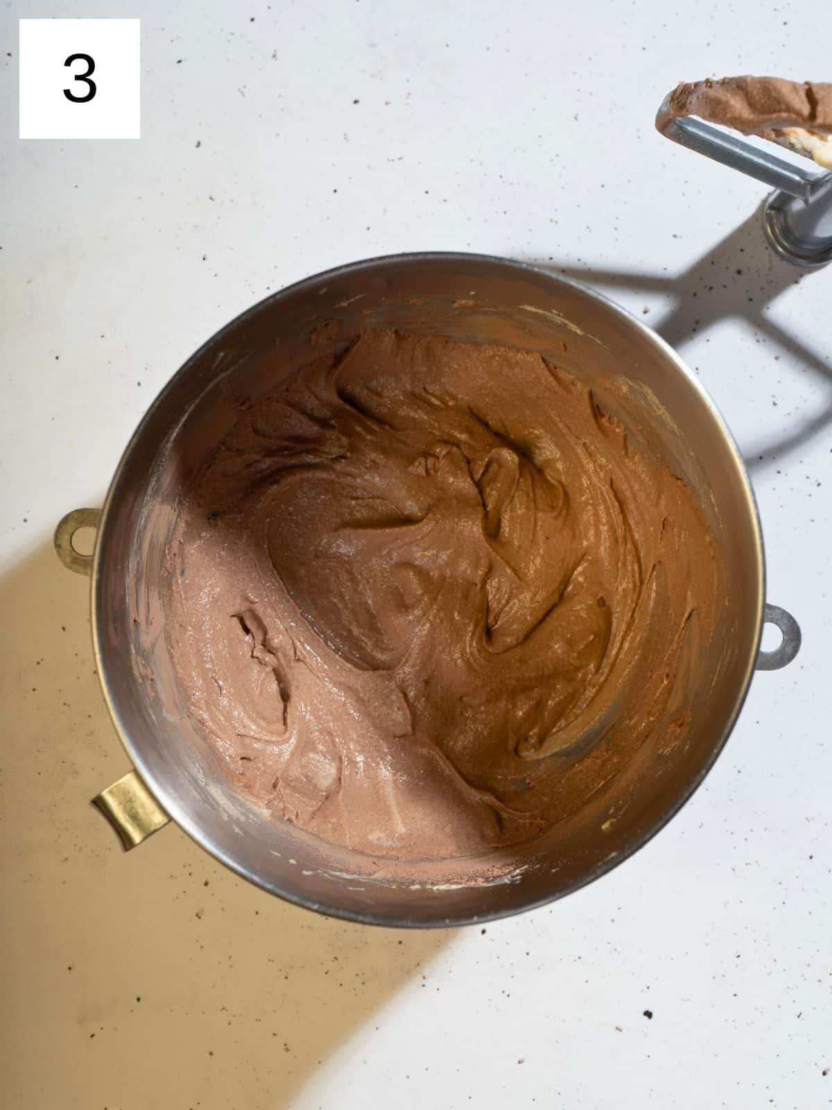 A large mixing bowl filled with whipped cream cheese ,butter, powdered sugar, brown sugar, cocoa powder, vanilla extract, and salt ready to be used in a delicious frosting or dip.
