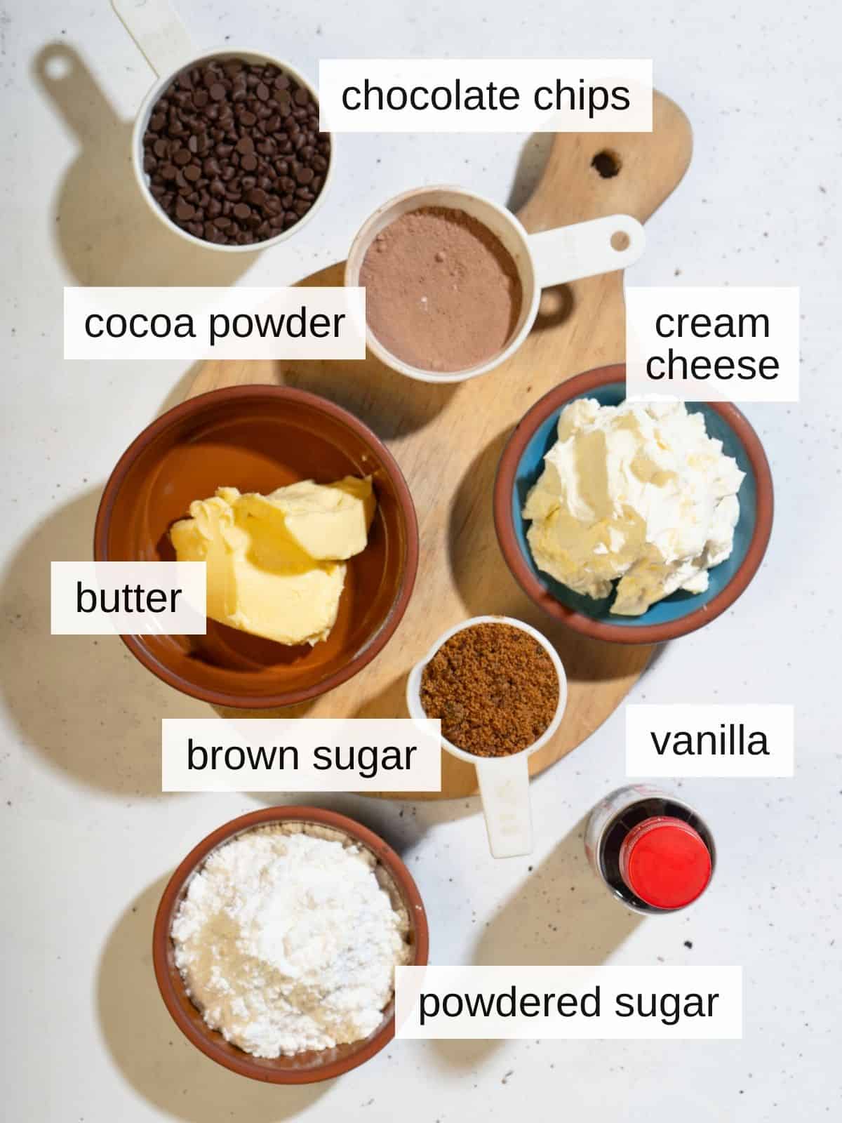 Ingredients for brownie batter dip, including chocolate chips, cocoa powder, cream cheese, butter, brown sugar, vanilla, and powdered sugar.