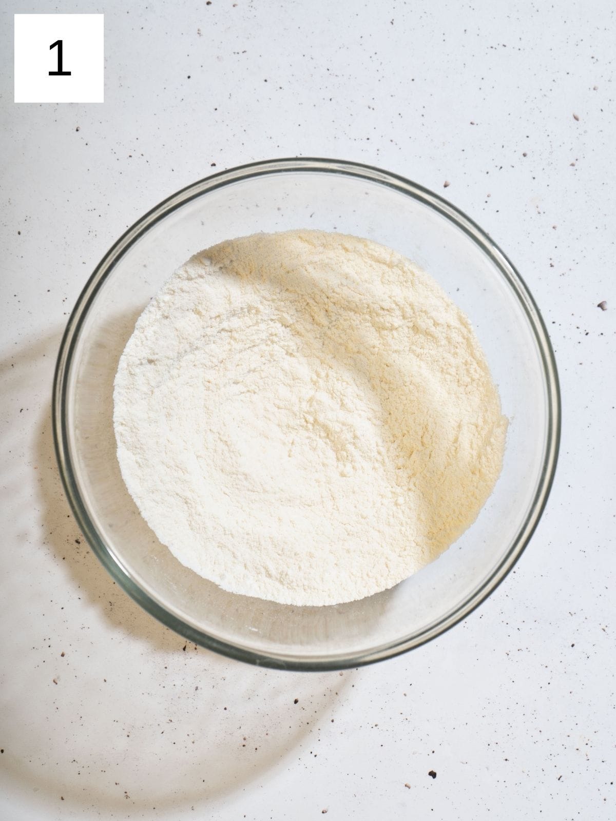 A bowl filled with mixture of flour, baking powder, and salt.