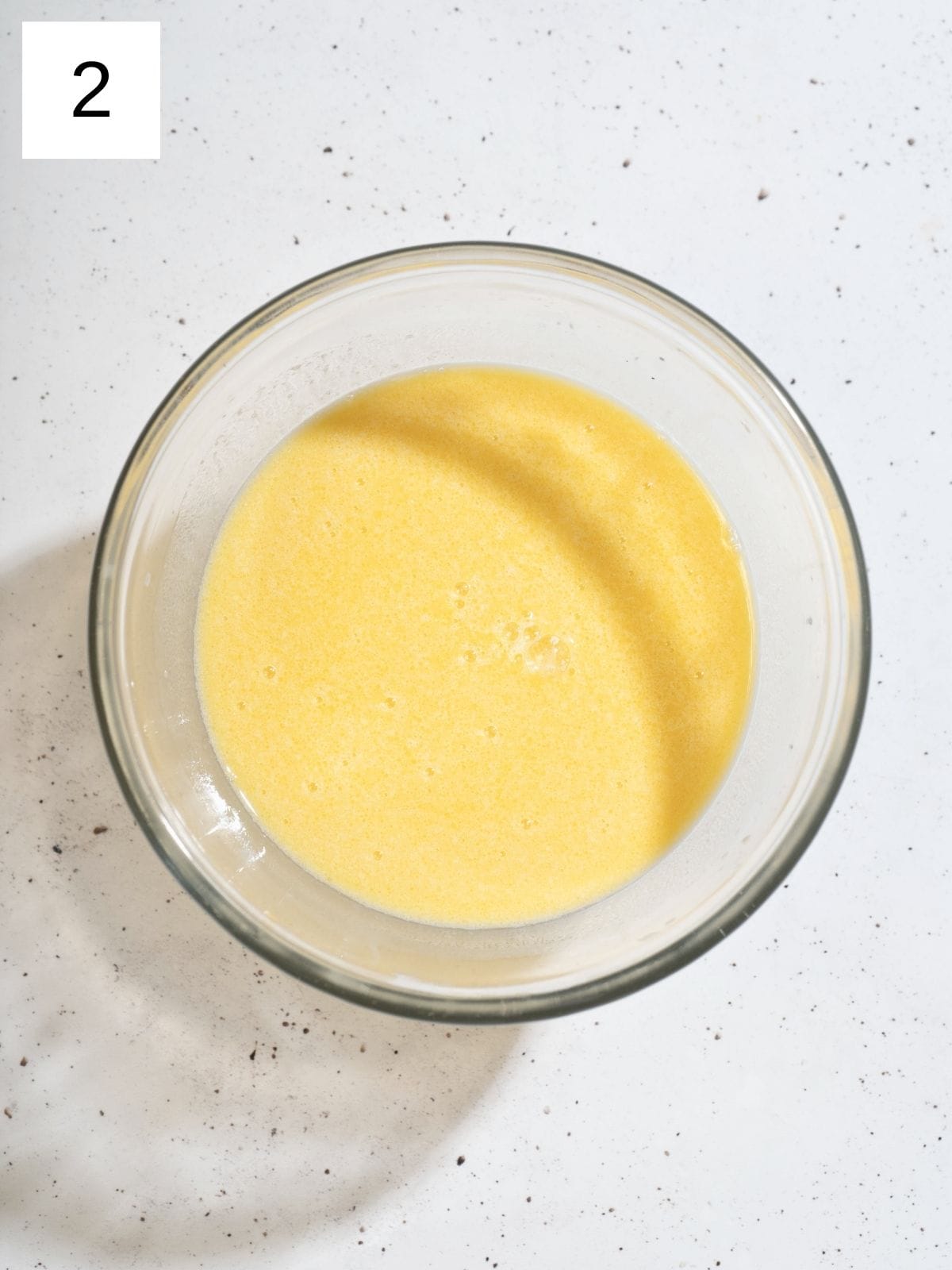 A bowl filled with mixture of milk, egg, melted butter, and vanilla extract.