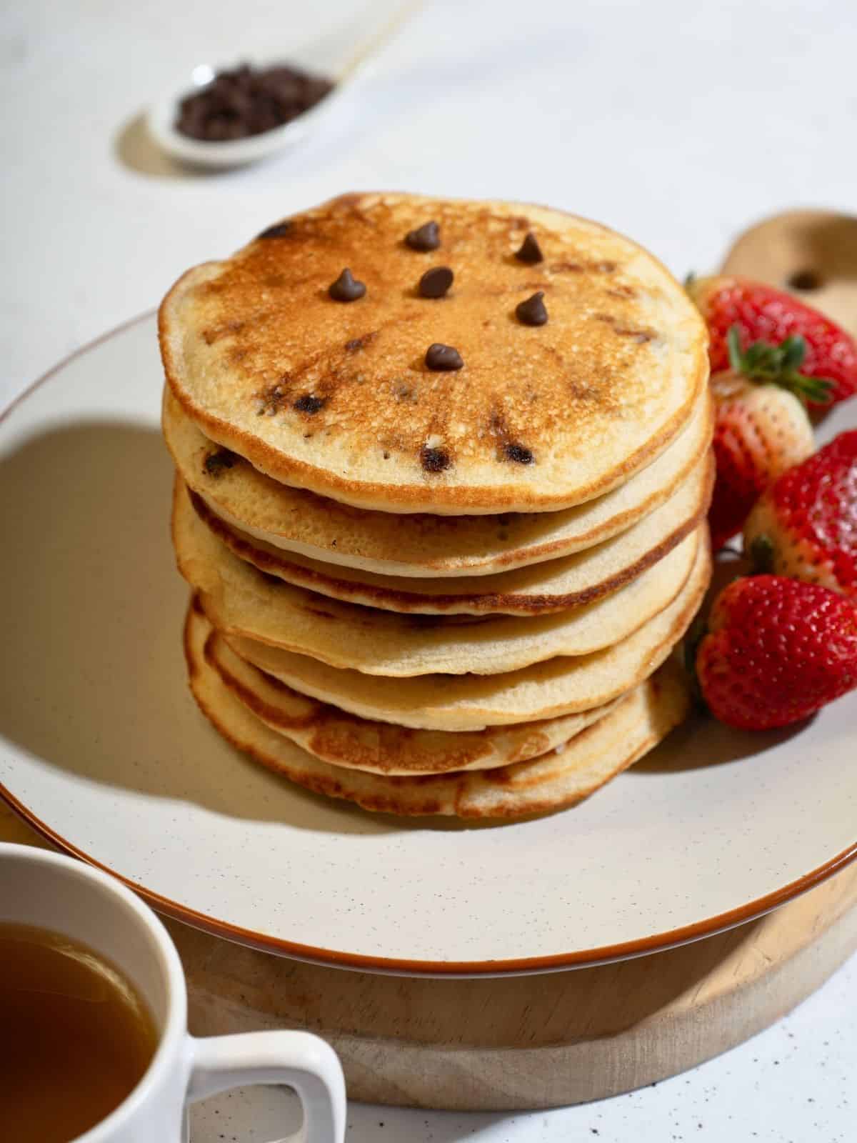 A stack of chocolate chip pancakes served with juicy strawberries, perfect for breakfast.