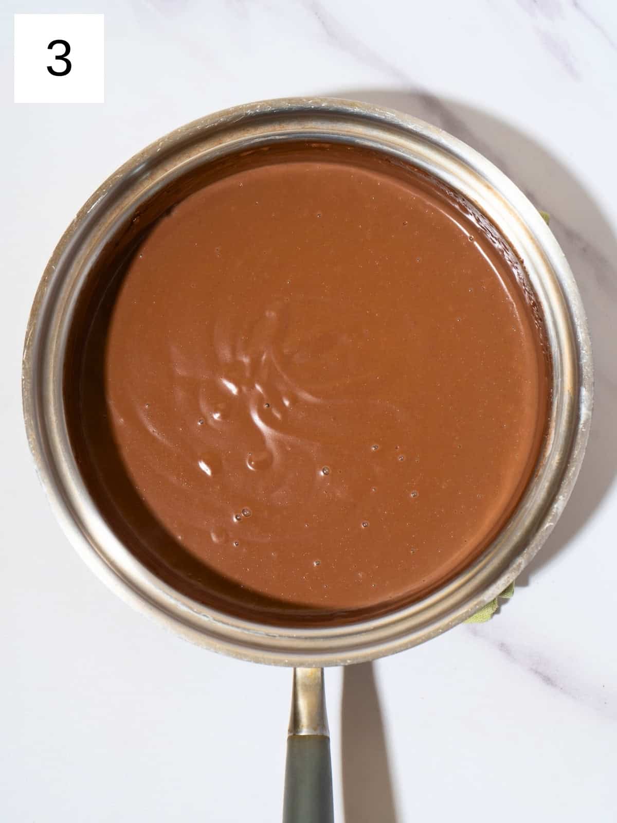 Thicken chocolate pudding mixture in a saucepan.