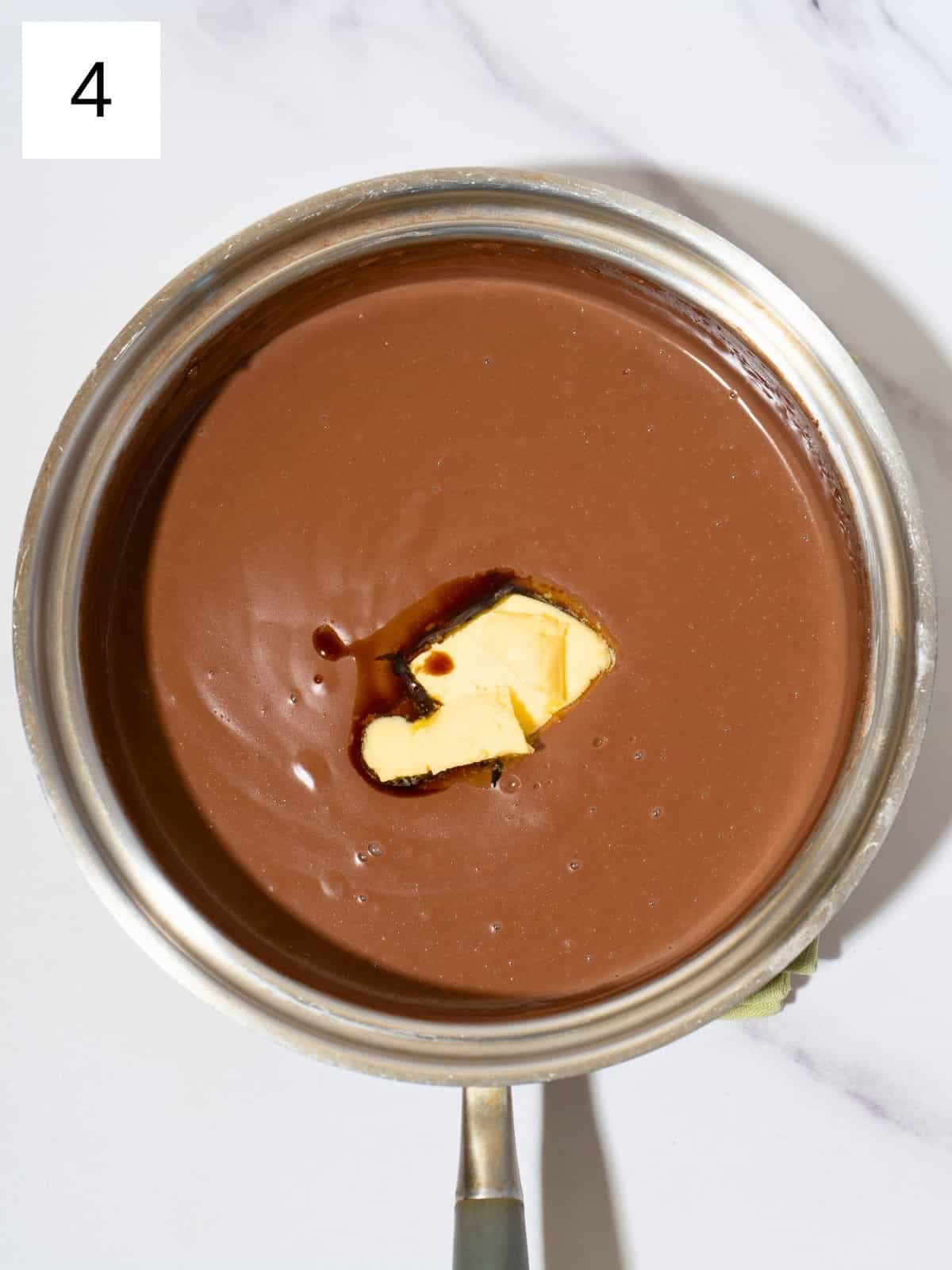 Thicken chocolate pudding mixture in a saucepan, stirred with sliced butter and vanilla extract.