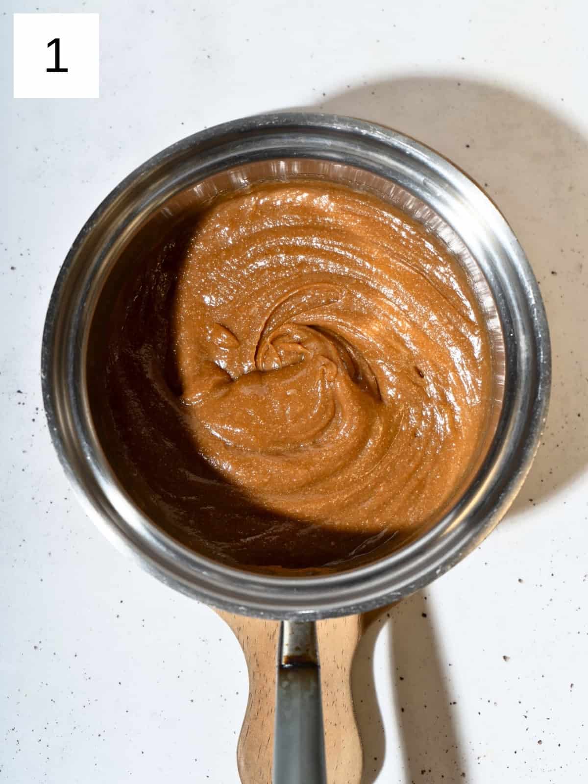 A mixture of peanut butter, maple syrup, salt, and vanilla extract in a a saucepan.