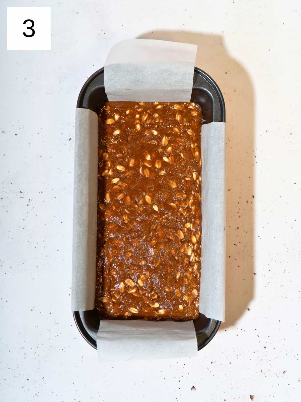 Peanut butter mixture spread in a parchment-lined loaf pan.