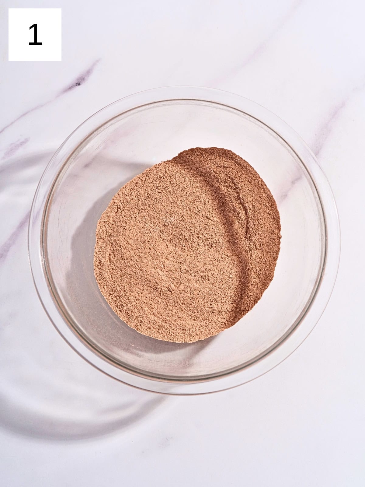 A mixture of flour, sugar, cocoa powder, baking powder, baking soda, and salt in a large mixing bowl.