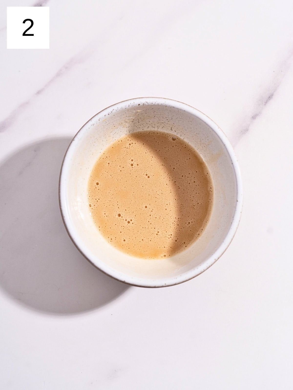 A mixture of vegetable oil. eggs, and vanilla extract in a separate bowl.