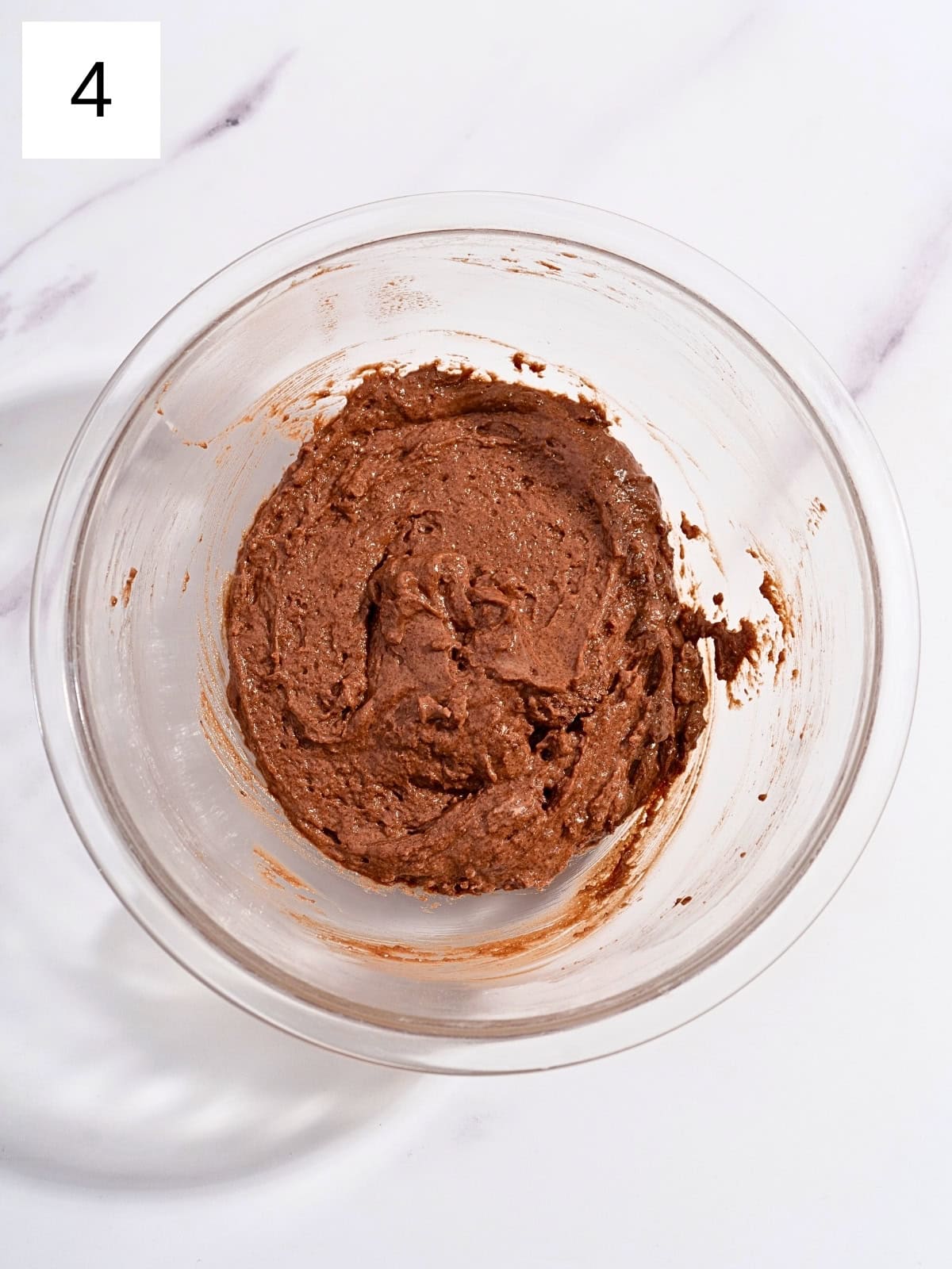 A mixture of dry chocolate mixture ingredients and egg mixture ingredients in a glass bowl.