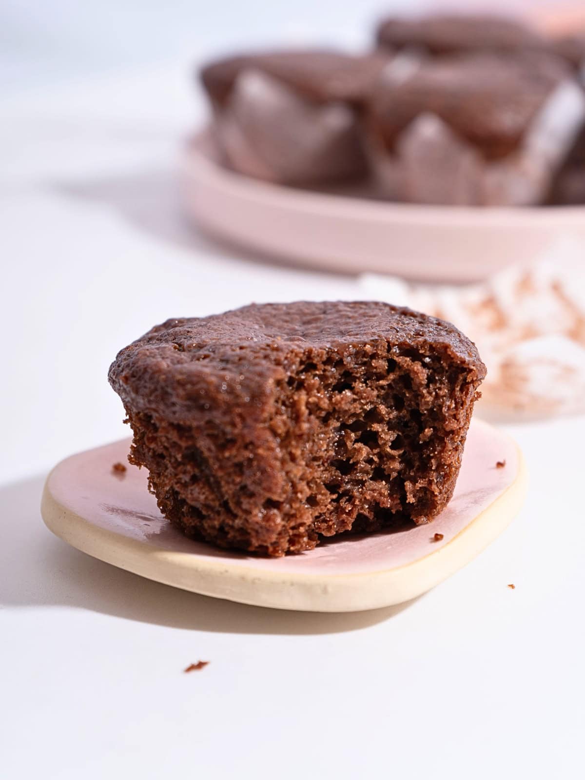 A bitten chocolate cupcake on a plate, revealing its moist and rich chocolate interior.