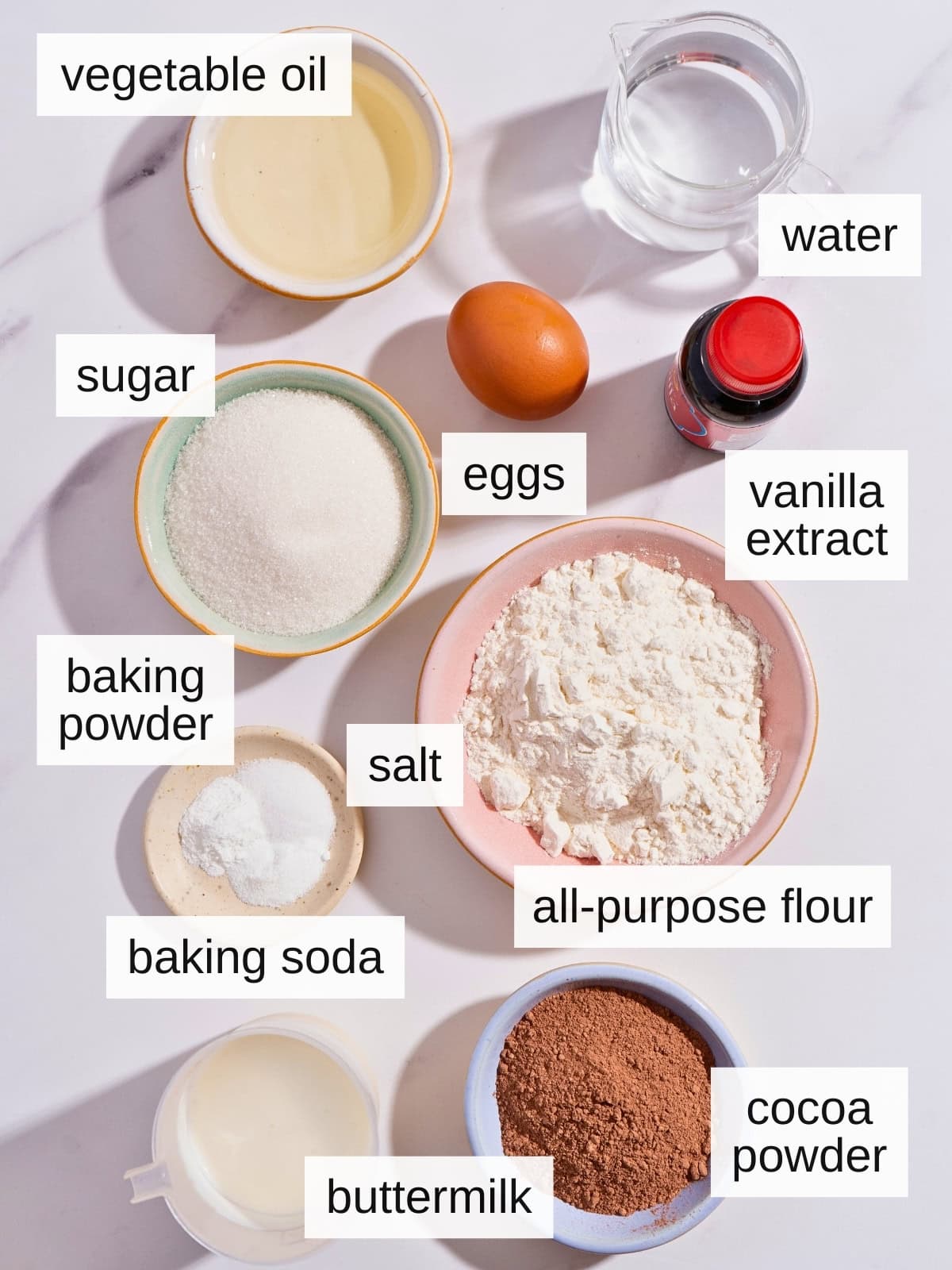 Ingredients for moist chocolate cupcakes, including vegetable oil, sugar, eggs, water, vanilla extract, baking powder, salt, baking soda, all-purpose flour, buttermilk, and cocoa powder.